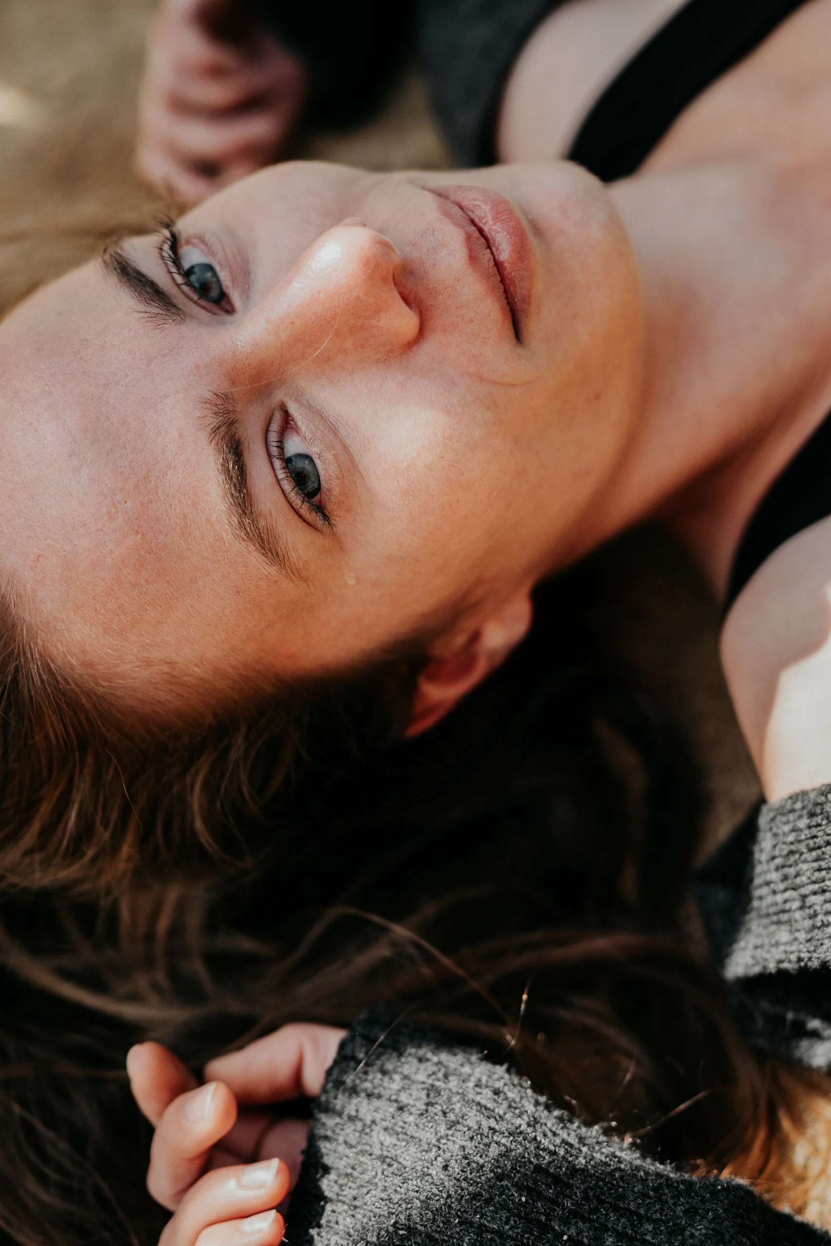 Nahaufnahme einer Frau, die entspannt auf dem Boden liegt, im natürlichen Licht.