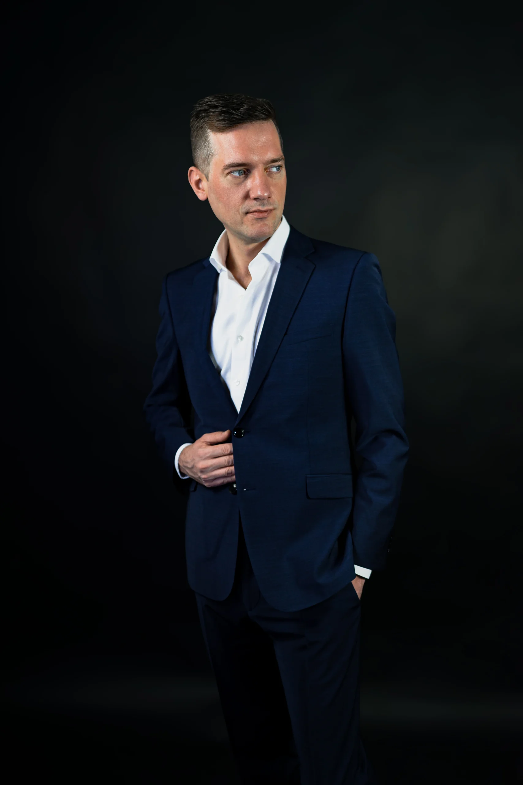 Mann im dunkelblauen Anzug vor dunklem Hintergrund. Stilvoll und professionell.